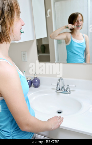 Ragazza giovane spazzolare i suoi denti in un bagno Foto Stock