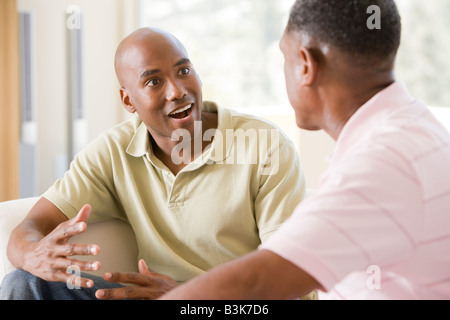 Due uomini in soggiorno a parlare e sorridente Foto Stock