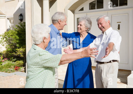 Due coppie senior saluto tra di loro con le braccia aperte Foto Stock