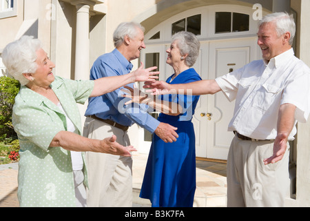 Due coppie senior saluto tra di loro con le braccia aperte Foto Stock