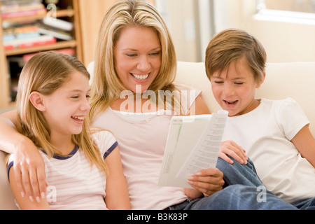 Donna e due bambini piccoli in sala lettura prenota e sorridente Foto Stock