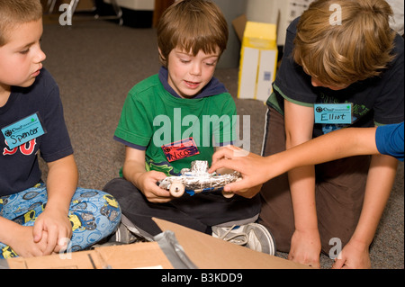 I bambini che mostra ogni altri veicoli realizzati da cartone riciclato e bottiglie di plastica in aula Foto Stock