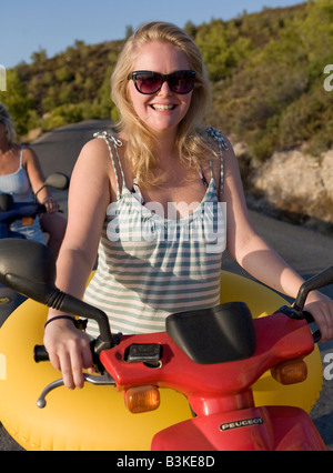 Donna che indossa anello gonfiabile seduto su uno scooter, Spetses, Grecia Foto Stock