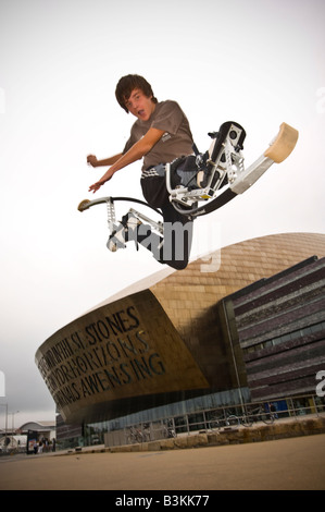 Giovane uomo su pogo rimbalzanti palafitte bockers facendo acrobazie al di fuori del Wales Millennium Centre Cardiff Bay Regno Unito Foto Stock