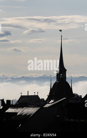 Silhouette di un campanile di una chiesa nella vecchia città di Bern centro, Svizzera. Le Alpi svizzere sono visibili in background. Foto Stock