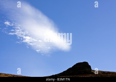 Una nuvola con la punta rivolta verso il basso verso Housey dirupi in cheviot hills, con un cielo blu in background Foto Stock