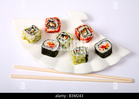 Il giapponese nori avvolto e futomaki uramaki california rotoli rotoli di sushi su una piastra bianca con bacchette Foto Stock