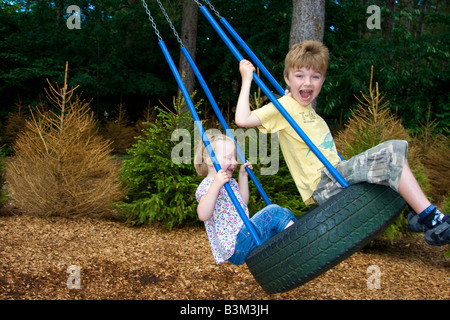 3 anno vecchia ragazza e 6 anno vecchio ragazzo sulla rotazione dei pneumatici Foto Stock