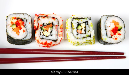 Il giapponese nori futomaki avvolto in corrispondenza di ciascuna estremità e riso avvolto uramaki California roll suchi rotola su una piastra con bacchette Foto Stock