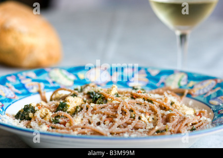 Spaghetti con formaggio di tofu spinaci e pomodori freschi con pane e un bicchiere di vino Foto Stock