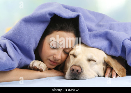 Il Labrador Retriever e giovane donna - giacente sotto la coperta Foto Stock