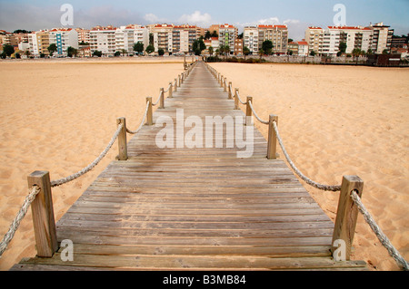 Un pedone passerella in legno si estende oltre le sabbie della spiaggia di Figueira da Foz,Portogallo,rivolta verso il centro della città. Foto Stock