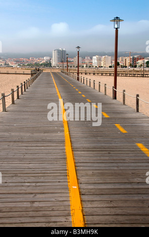 Un pedone passerella in legno si estende oltre le sabbie della spiaggia di Figueira da Foz,Portogallo,rivolta verso il centro della città. Foto Stock