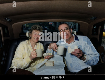 Jim Bowen il presentatore TV Bullseye seduti nella parte posteriore di una Rolls Royce con la sua ife Phyllis Bowen mangia bacon butties Foto Stock