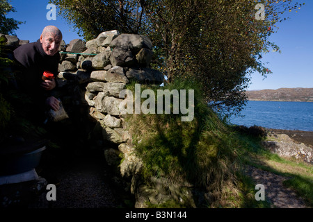 Tatuato eremita Tom Leppard emerge dall'ingresso del suo segreto rifugio improvvisato rifugio a Skye Scozia Scotland Foto Stock