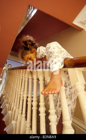 Bambina lo scorrimento verso il basso ringhiera di scala Foto Stock