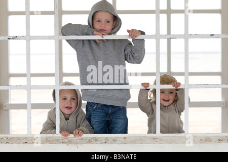 Tre bambini borthers e sorella guardando attraverso le barre di un rifugio di fronte al mare a Weston-super-Mare Foto Stock