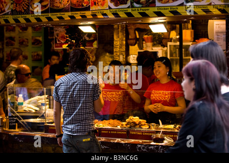 Londra , stalle di Camden Market , pretty ragazze sorridenti servire cinese & Oriental prelibatezze presso street o fast food in stallo Foto Stock