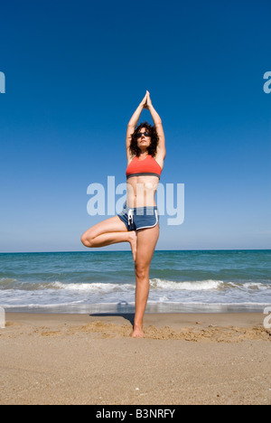 Modello rilasciato montare giovane donna fare yoga stretching esercizi di stretching su di una spiaggia di sabbia Foto Stock