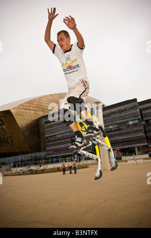 Giovane uomo su pogo rimbalzanti palafitte bockers facendo acrobazie al di fuori del Wales Millennium Centre Cardiff Bay Regno Unito Foto Stock