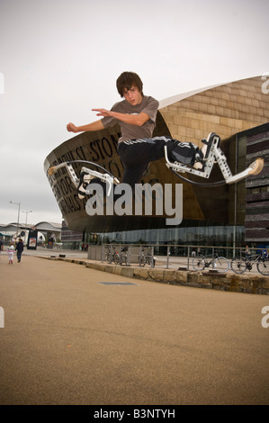 Giovane uomo su pogo rimbalzanti palafitte bockers facendo acrobazie al di fuori del Wales Millennium Centre Cardiff Bay Regno Unito Foto Stock