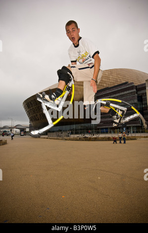 Giovane uomo su pogo rimbalzanti palafitte bockers facendo acrobazie al di fuori del Wales Millennium Centre Cardiff Bay Regno Unito Foto Stock