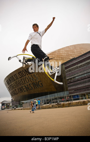 Giovane uomo su pogo rimbalzanti palafitte bockers facendo acrobazie al di fuori del Wales Millennium Centre Cardiff Bay Regno Unito Foto Stock