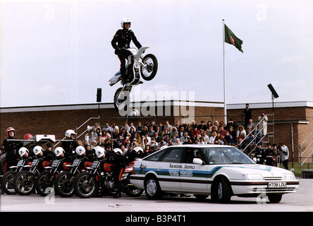 Army Regiments Royal segnali caschi bianco sulla moto facendo uno stunt su una macchina Foto Stock