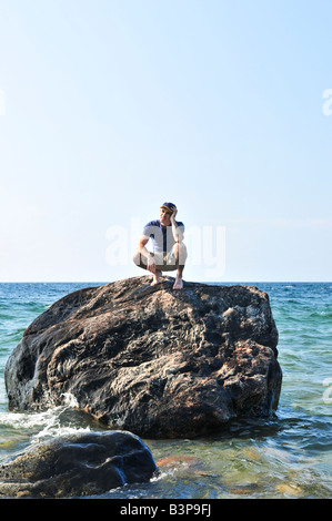 L'uomo arenati su una roccia nel mare in attesa di aiuti per il salvataggio Foto Stock