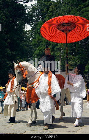 Giappone, Prefettura di Tochigi, Nikko. Festival di Primavera al Santuario di Toshogu dinastia Tokugawa uomini in costume tradizionale a cavallo portante Ombrellone rosso Foto Stock