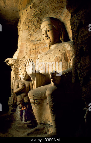 Cina, Datong. Visitatore accanto a una delle statue del Buddha al quinto secolo le grotte di Yungang, una serie di grotte buddista Foto Stock