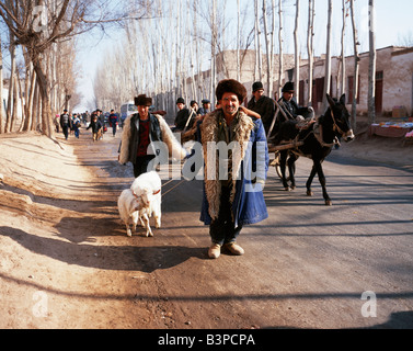 Cina, provincia dello Xinjiang, Kashgar. Uighur uomo con pecora su strada a Kashgar mercato. Foto Stock