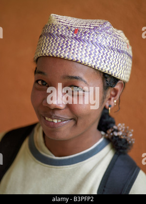 Est del Madagascar, Perinet. Un malgascio bambina indossa un tessuto localmente hat. Il Madagascar è ben noto per la straordinaria varietà e stili della sua locale cappelli, che variano notevolmente da regione a regione. Fibre diverse sono utilizzati per la tessitura del cappelli a seconda della disponibilità; essi includono palms (rafia, badika, manarana e dara) o paglia. Foto Stock