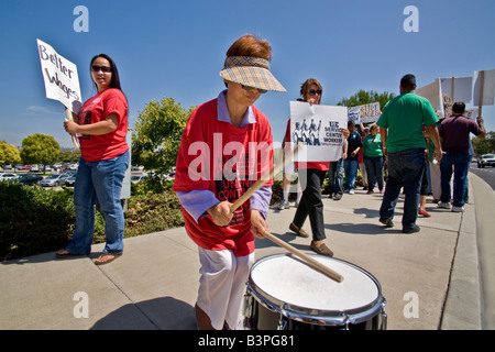 Una donna asiatica batte un tamburo come unione dipendenti di U S governo appaltatori picket per una migliore retribuzione e condizioni di lavoro Foto Stock