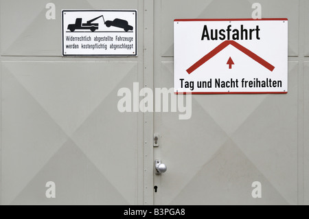 Porta di garage, grigio metallo porta di garage con segni, mantenere libero di giorno e di notte e veicoli parcheggiati illegalmente verrà trainato all'ow Foto Stock