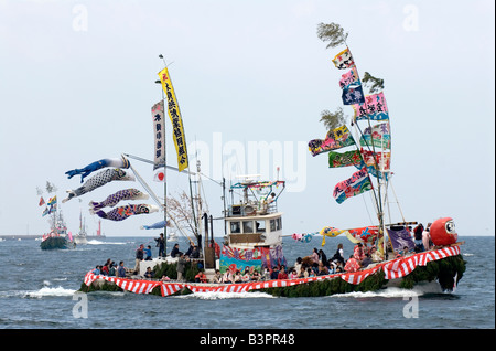 Barca da pesca decked out in banner colorati e cantare i membri dell'equipaggio per la Ose Matsuri festival nei pressi di Numazu Giappone Foto Stock