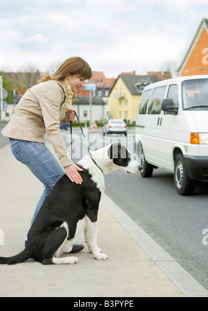 Donna con metà del cane di razza - in piedi alla strada / Foto Stock