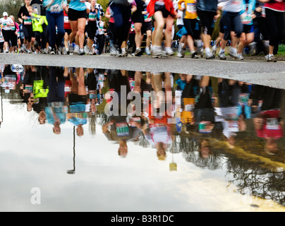 Corridori della maratona riflessa nella pozzanghera Foto Stock