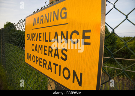 Segnale di avvertimento per le videocamere di sorveglianza sulla rete di recinzione a maglie protezione della proprietà privata Foto Stock