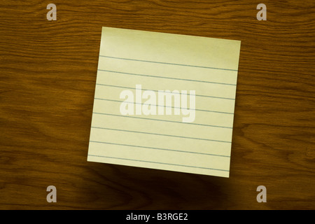 Rivestito in bianco bigliettino giallo su sgranate Sfondo legno Foto Stock
