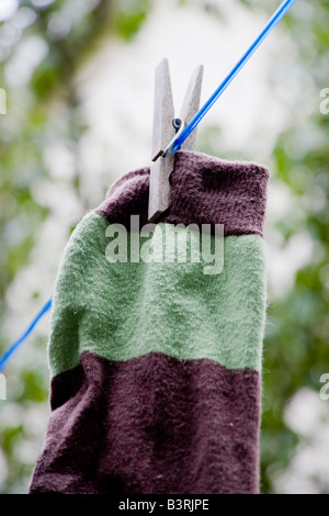 Un calzino essiccazione su una linea di lavaggio e viene trattenuto da un picchetto in legno Foto Stock