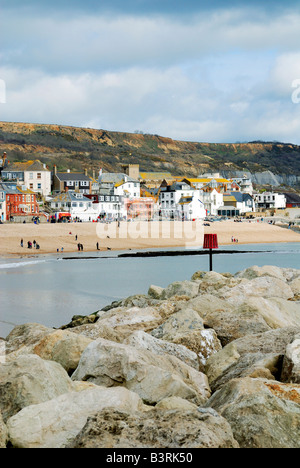 Spiaggia di sabbia sul lungomare a Lyme Regis nel Dorset con sole splendente e un buio cielo nuvoloso Foto Stock