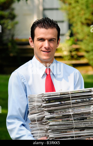 Ambiente uomo cosciente che porta una pila di giornali per essere riciclata Foto Stock