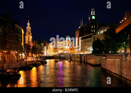 Amsterdam canale Singel a bella notte tranquilla con barche e colorata illuminazione con riflessioni, Paesi Bassi Foto Stock