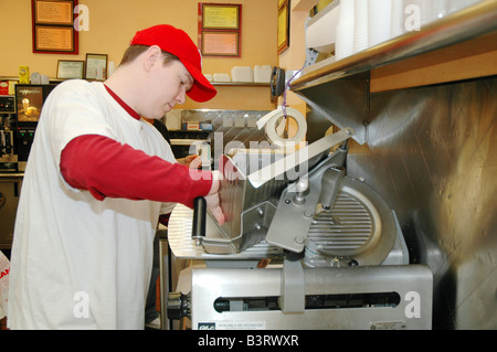 L'uomo il taglio di carne a fette sulla macchina affettatrice a un deli brooklyn new york Foto Stock