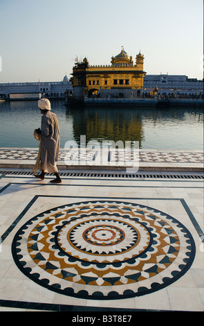 India Punjab , Amritsar. Un pellegrino di seta balade accanto l' amrit Sarovar, il 'Pool di nettare Immortality-Giving', e il Tempio Dorato. Foto Stock