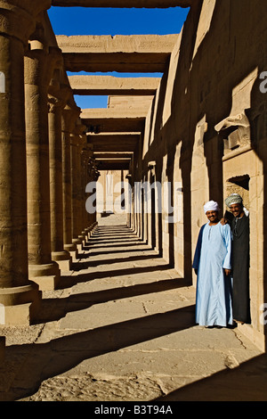Due uomini egiziano e colonne che gettano ombre e il Tempio di Philae, su Agilika, un'isola del fiume Nilo, vicino a Aswan, Egitto. Foto Stock