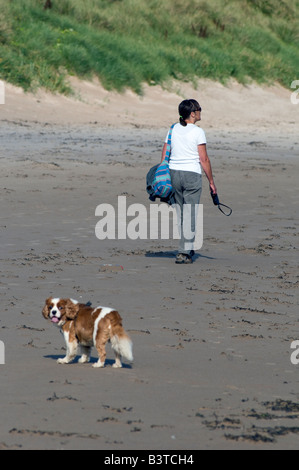 Donna che cammina il suo cane sulla spiaggia Foto Stock