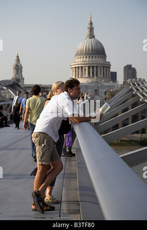 Inghilterra, Londra. I turisti mettere in pausa per prendere in vista lungo il Tamigi dal Millennium Bridge. Foto Stock