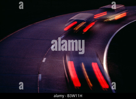 La sfocatura delle luci di coda sulle autovetture in movimento al crepuscolo Foto Stock